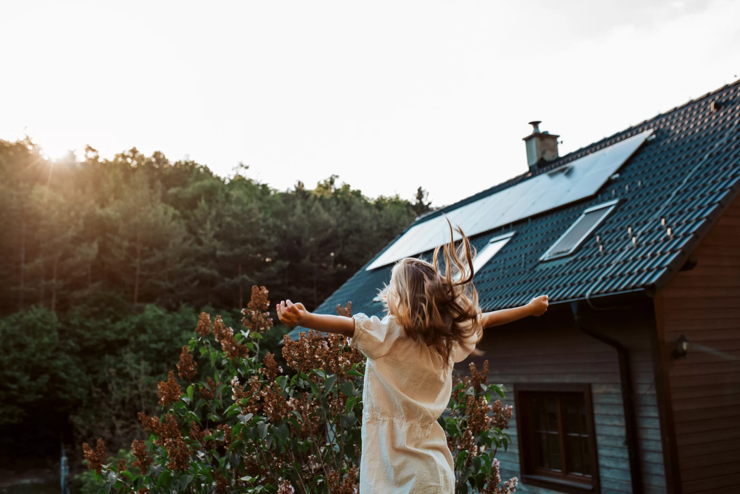 Jeune fille heureuse devant sa maison avec une solution de panneaux solaires photovoltaïques