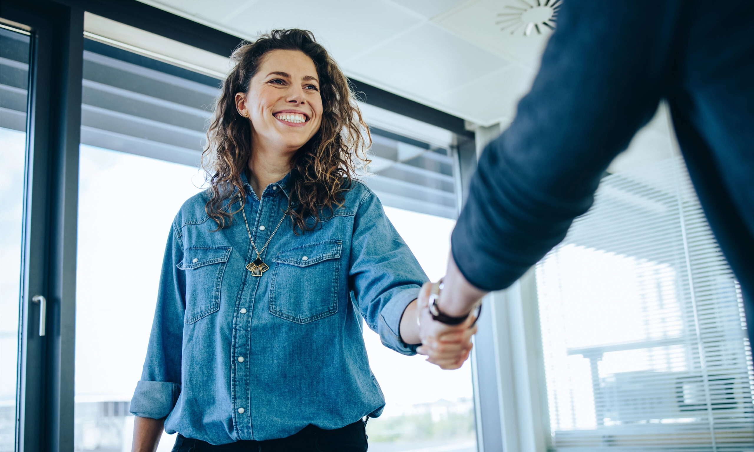 Femme souriante au travail serrant la main d'une autre personne