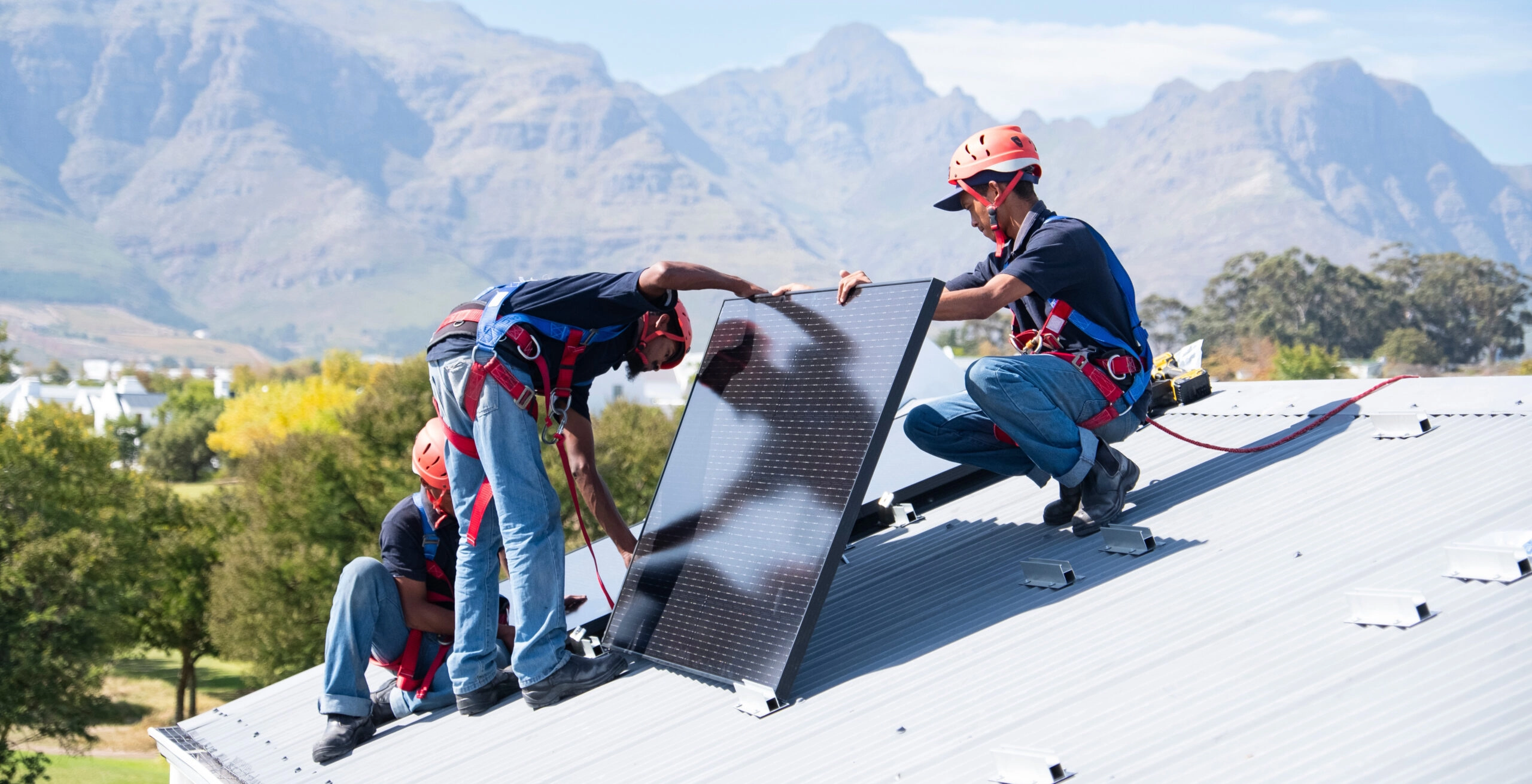 Vue de trois techniciens installant des panneaux solaires photovoltaïques sur le toit d'une maison en montagne