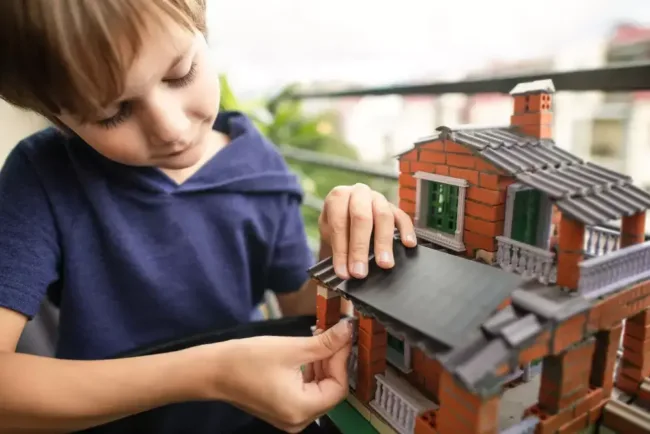 Enfant en train de construire une maison en brique