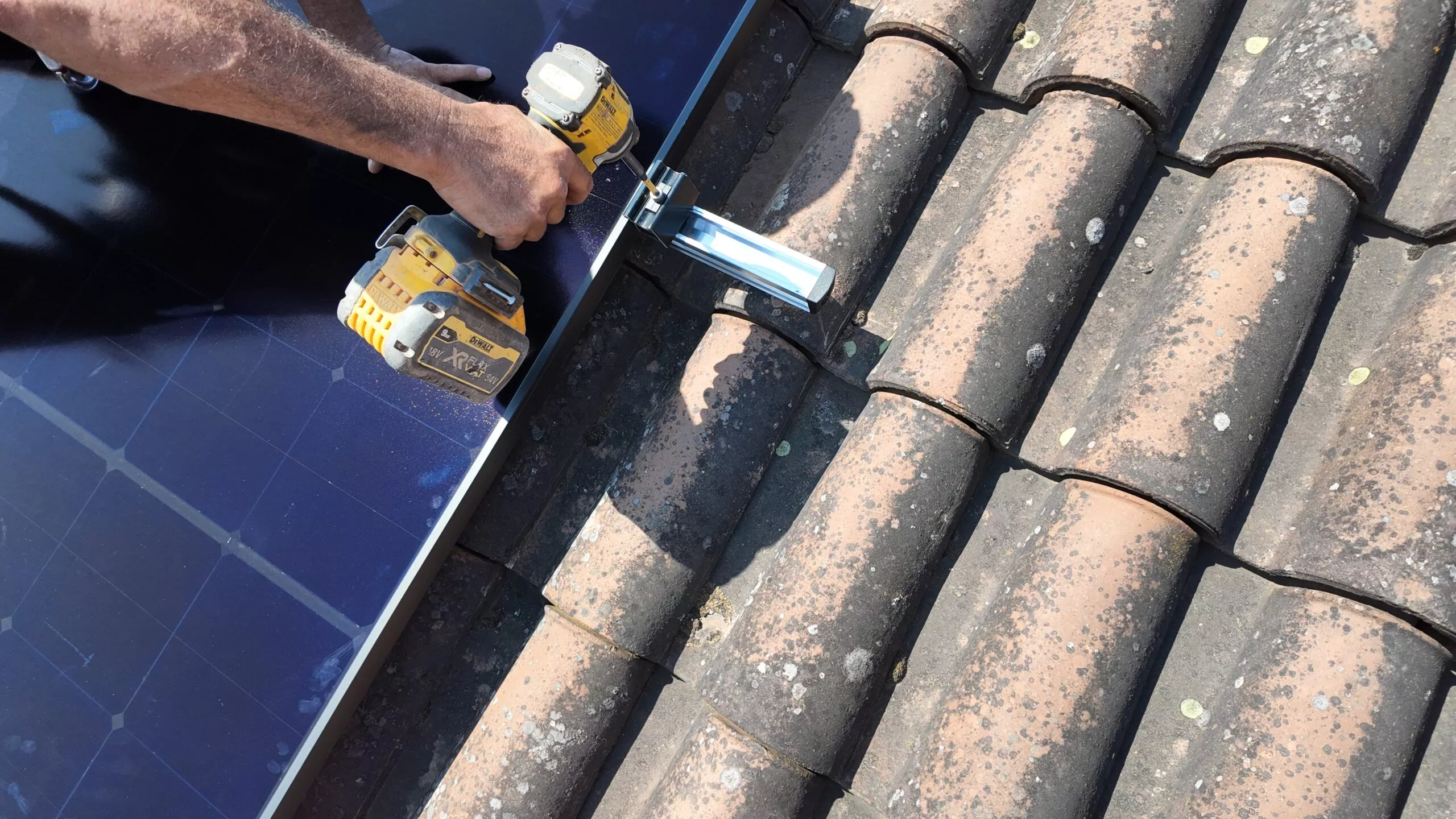 Zoom sur un technicien en train d'installer un panneau solaire sur le toit d'une maison