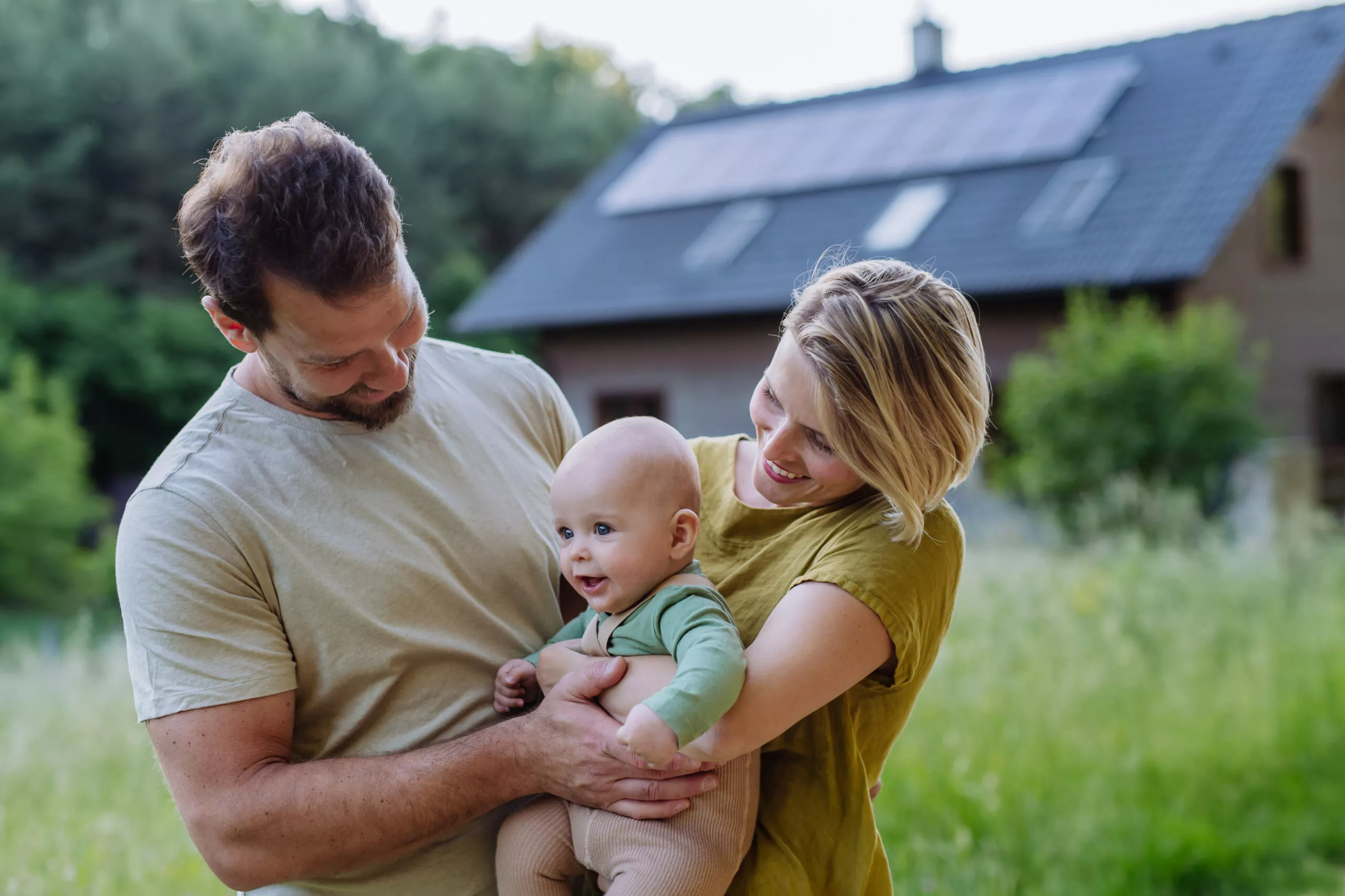 Famille heureuse près de sa maison équipée de panneaux solaires. Concept d'énergie alternative, d'économie de ressources et de mode de vie durable.