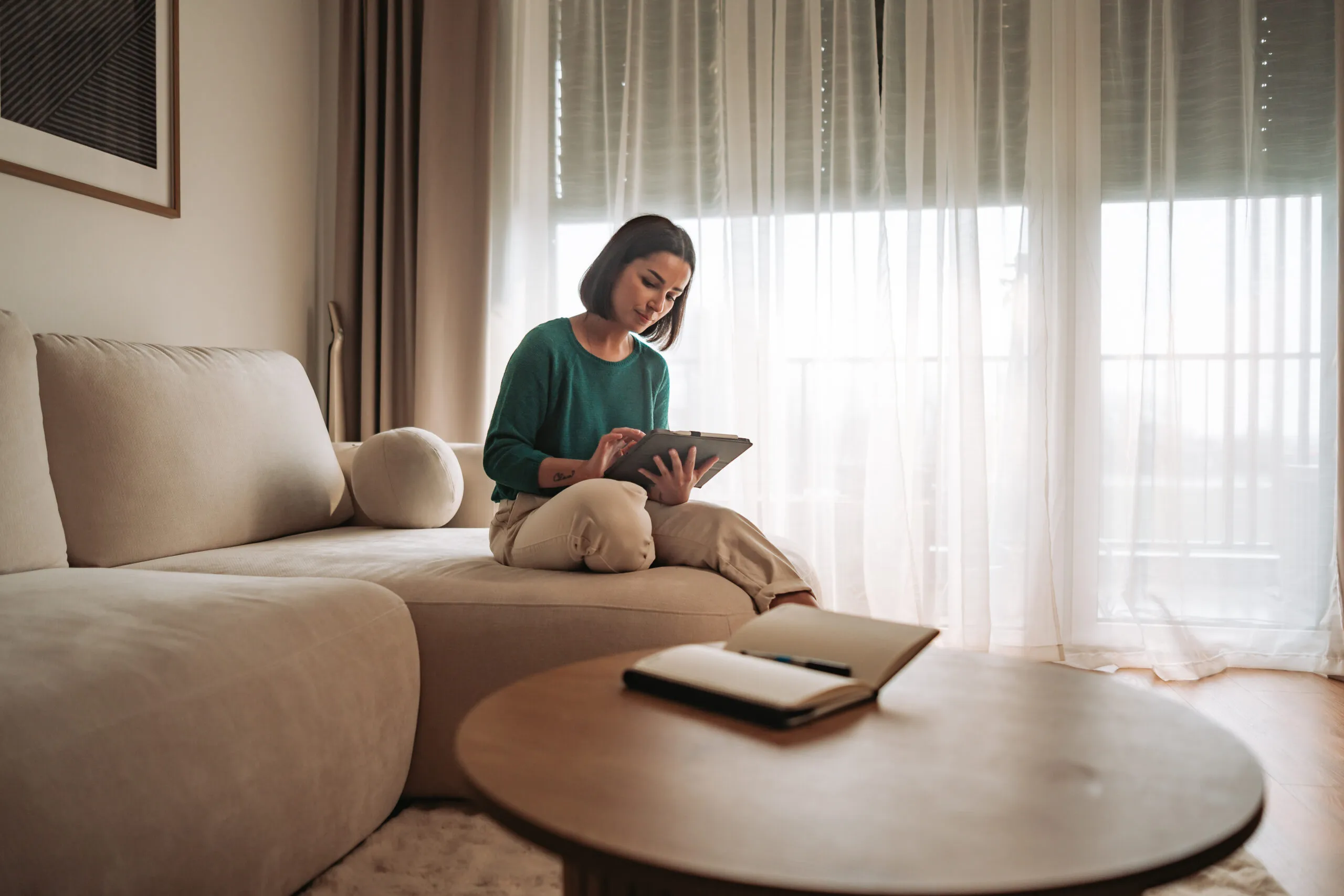 A woman on a sofa using a tablet, illuminated by beautiful natural light