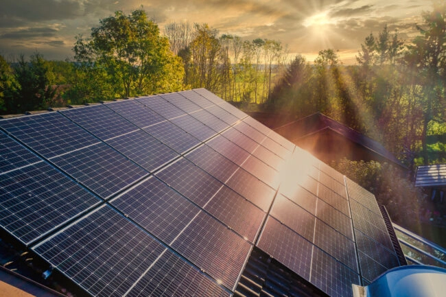 panneaux solaires sur une maison devant un forêt coucher de soleil
